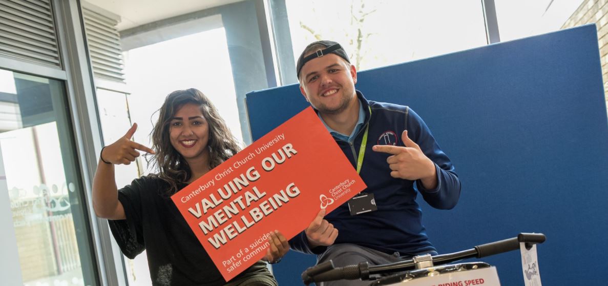 Two Canterbury Christchurch University students holding up poster saying Valuing our mental wellbeing