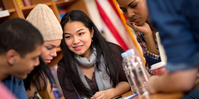 Group of five students sat at a table in a library