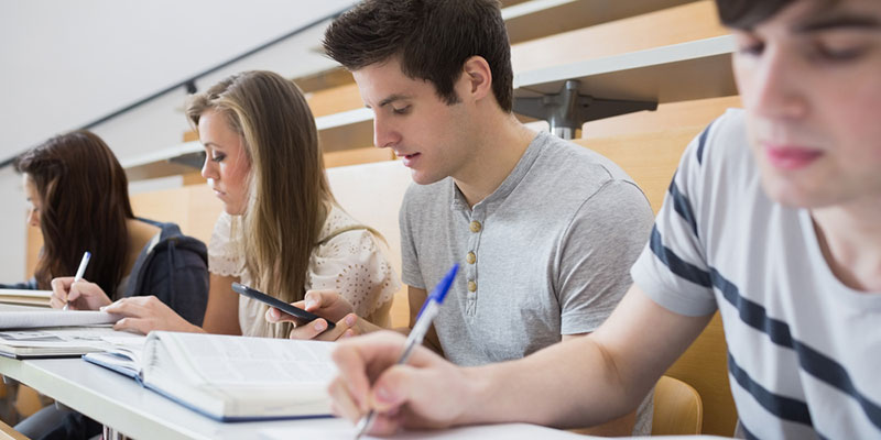 Four students taking notes in a lecture theatre