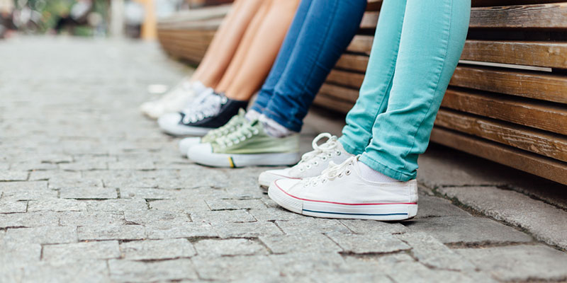 Legs of four students wearing trainers in a public place