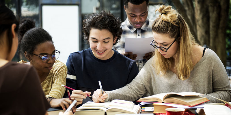 Three students working together looking at books