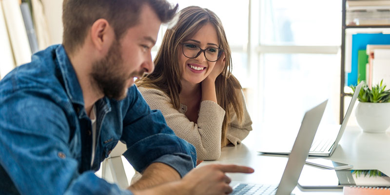 Two employees looking at a laptop