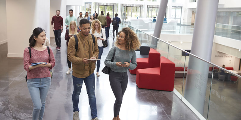 Three students walking through a university building