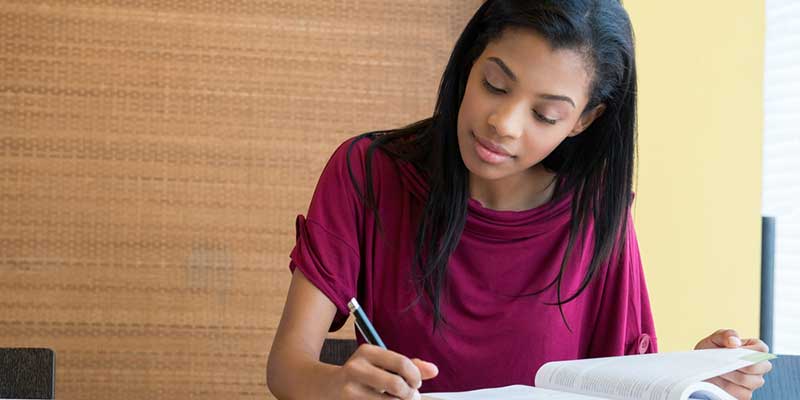 Woman making notes from a book