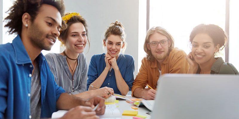 Group of five students around a laptop