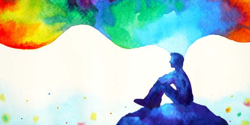 abstract image of person sitting on hill with colours floating around them