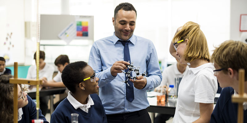 Science teacher showing a model to a group of teenagers