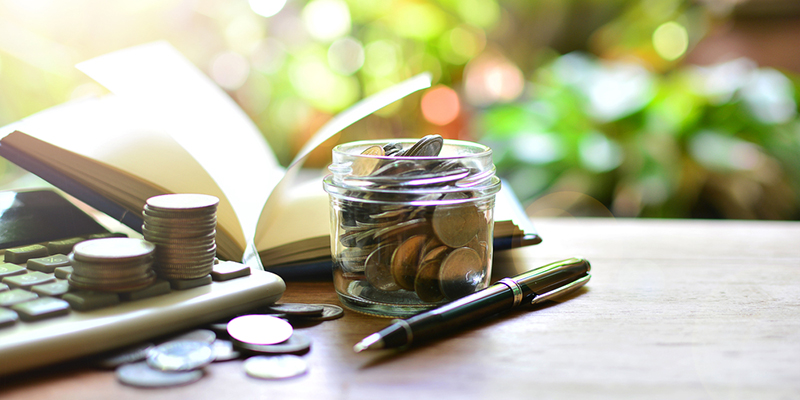 A jar of coins, calculator, pen and open book