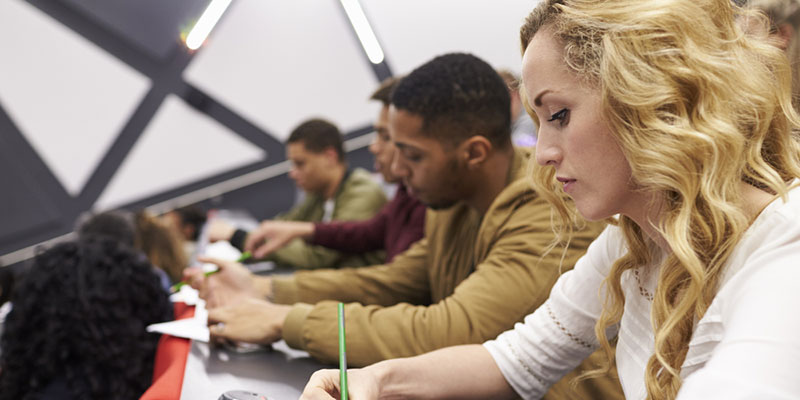 Several students taking notes during a lecture