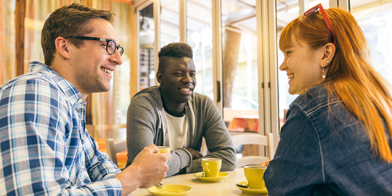 Three students in a coffee shop talking