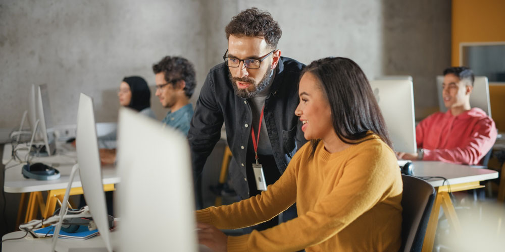 Apprentice sharing her work on PC screen with employer in modern office