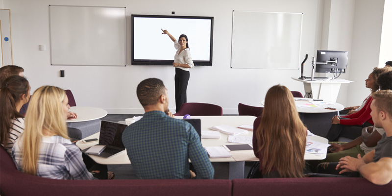 Teacher pointing to whiteboard in seminar with small group of university students