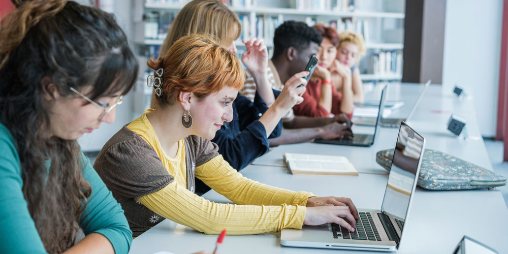 students in university classroom working at laptops