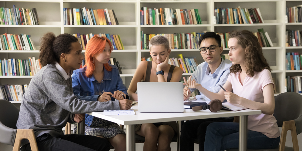 five students sat in university library having a serious discussion