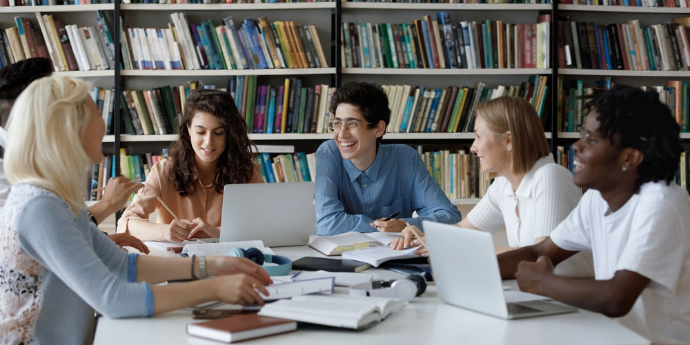 students sat around a table in a university library talking